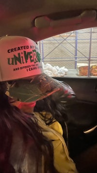 a woman in a car wearing a hat that says created the universe