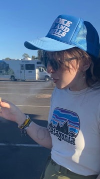 a woman smoking a cigarette in a parking lot